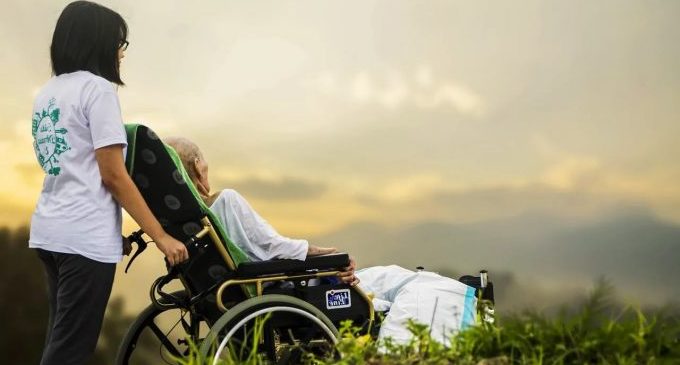 молодая девушка гуляет с бабушкой в инвалидном кресле