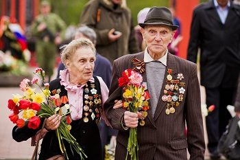 пожилая семейная пара, ветераны войны с цветами