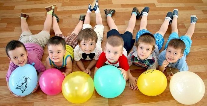 дети лежат на полу с воздушными шариками
