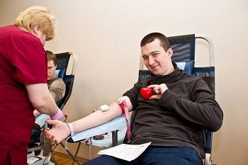 донор крови во время процедуры держит игрушечное сердечко
